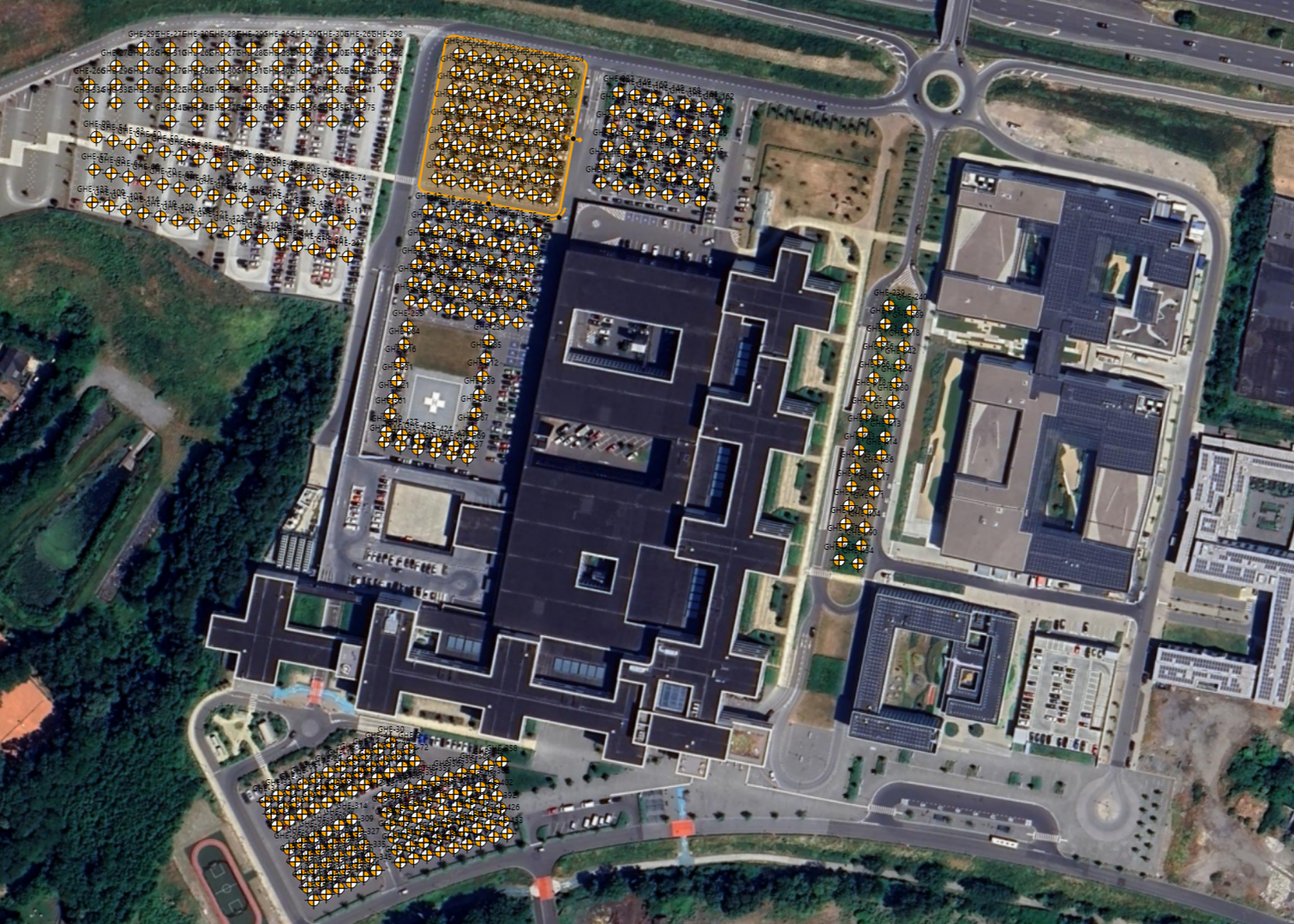 Aerial view of a large industrial or commercial complex with a field of geothermal boreholes.
